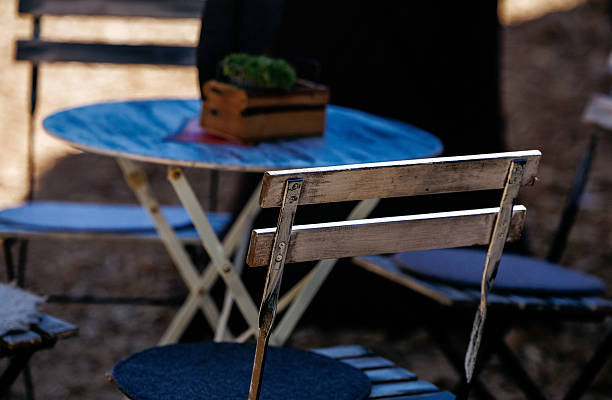 Rustic outdoor cafe setting with wooden chairs and tables in sunlight, lifestyle