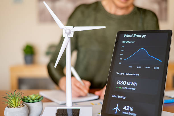 istock Person analyzing wind energy data on a digital tablet next to a miniature wind turbine model, symbolizing sustainable energy management and ecological future planning 2239884370