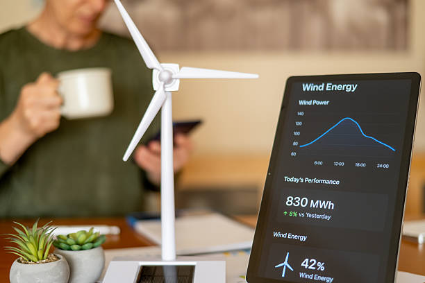 istock Person reading wind power generation data on a digital tablet with a desktop wind turbine model, symbolizing sustainable energy management and green technology 2239884398