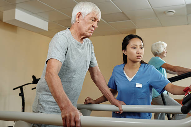 istock Aged Man Walking on Treadmill under Control of Young Nurse 2239887548