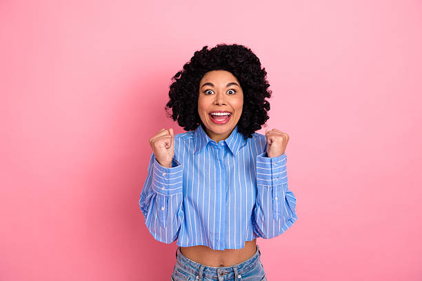 istock Cheerful young woman celebrates with joyful expression while standing against a vibrant pink background. 2239889237