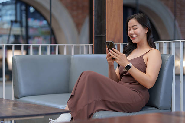 istock Woman smiling and texting on smartphone in cafe 2239889906