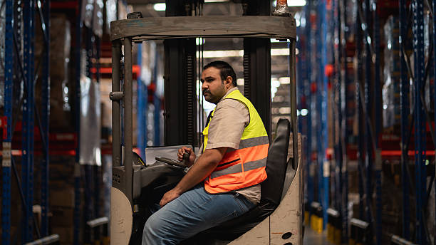 istock Warehouse worker operating forklift with safety helmet and reflective vest, symbolizing logistics, supply chain efficiency, shipping, and industrial warehouse operations. 2239894073