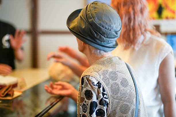 A woman wearing a hat and a white shirt is sitting at a table with her hands on her lap