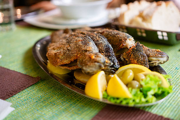 Restaurant specializing in traditional fried trout fish, serving a fresh platter with lemon wedges and green olives