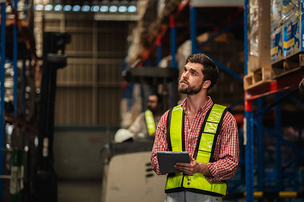 istock Warehouse workers and manager in reflective vests inspecting inventory, using digital tablet for stock control, logistics, supply chain management, and modern industrial warehouse operations. 2239895330