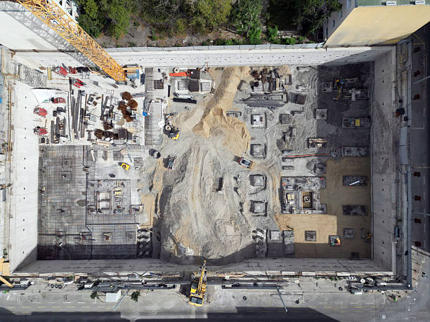 Aerial view construction site with a foundation pit of new skyscraper timelapse. Earthwork in excavation and backfilling of soil. Heavy machinery for earthmoving with crane, truck and bulldozer. stock photo