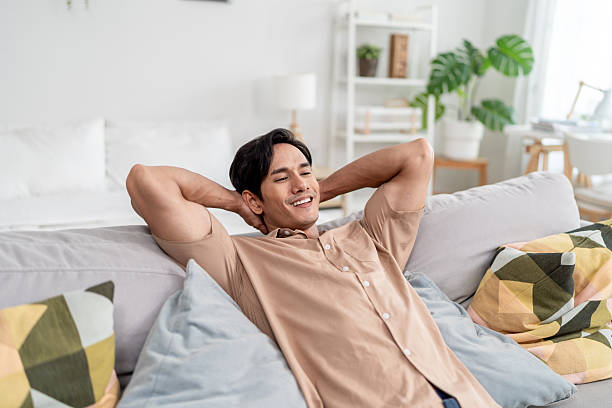 istock Asian handsome man lying down on comfortable sofa in living room at home. Young attractive guy feel happy and relax, enjoying leisure time during holiday vacation in house. Healthy wellness concept. 2239897341