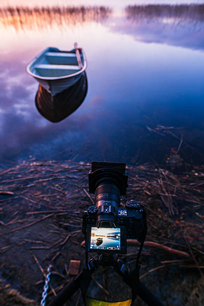 istock Digital camera capturing a boat on a still lake during sunset in calm surroundings 2239898727