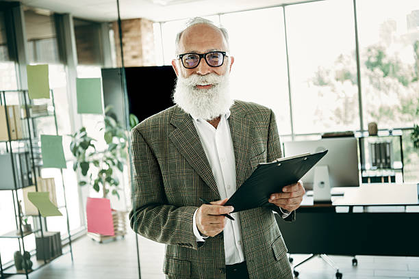 istock Confident senior businessman with white beard holding clipboard in modern office setting reflecting professionalism 2239898858