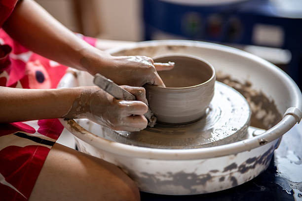 istock Woman pottery artist using tool scraping clay tea brewing bowl on throwing wheel in class or studio 2239899723