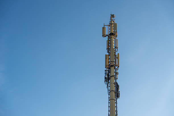 A cell phone tower rises high into the blue sky.