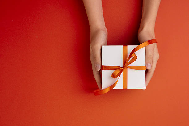 Hands holding gift box top view empty copy space decorated with red ribbon.Christmas background,backdrop.new year template,Valentine's day.
