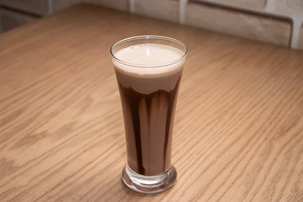 Chocolate Milkshake in a Tall Glass with Syrup Drizzle on a Wooden Table side view
