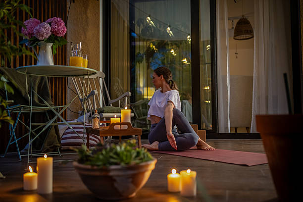 istock Woman Practicing Yoga on Patio Surrounded by Candlelight and Decor 2239905791