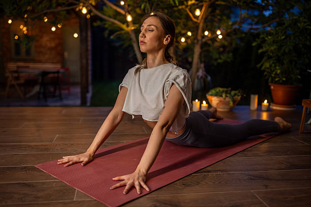 istock Woman Practicing Yoga Outdoors at Night With Peaceful Candlelit Ambiance 2239906122