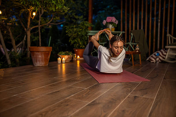istock Woman Practicing Yoga Outdoors at Night Amid Relaxing Candlelight and Greenery 2239906149