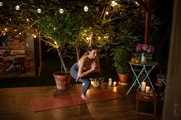 istock Woman Practicing Yoga Poses Outdoors at Night Surrounded by Candlelight 2239906533