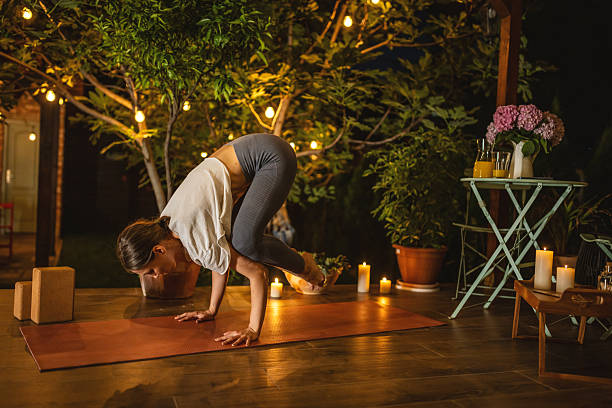 istock Woman Practicing Arm Balance Yoga Pose Outdoors at Night Amid Candlelight 2239908135