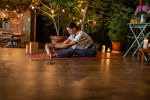 istock Woman Practicing Yoga Outdoors Surrounded by Decorations and Warm Lighting 2239908185