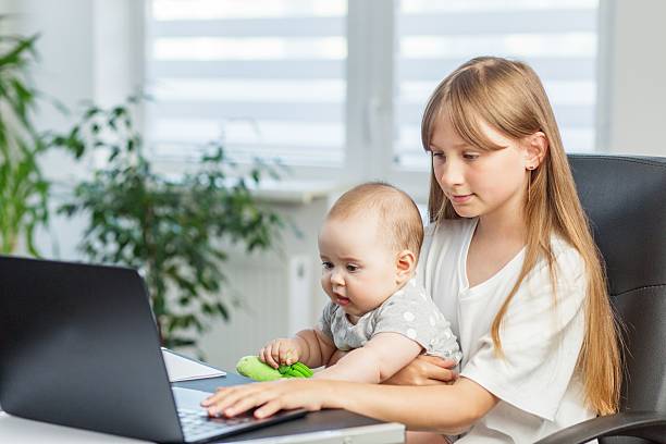 istock Girl holding baby while using laptop 2239909346