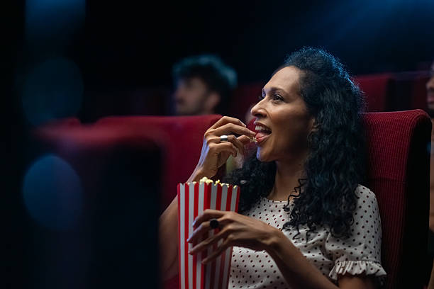 istock Mature Hispanic Female Enjoying Cinema Experience with Popcorn 2239910712