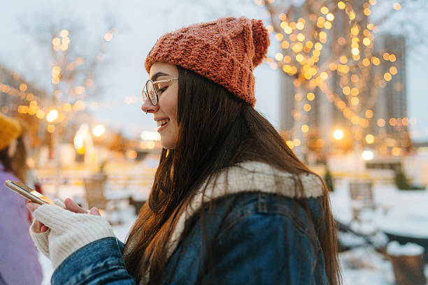 istock Young woman using her mobile phone while at Christmas market 2239912349