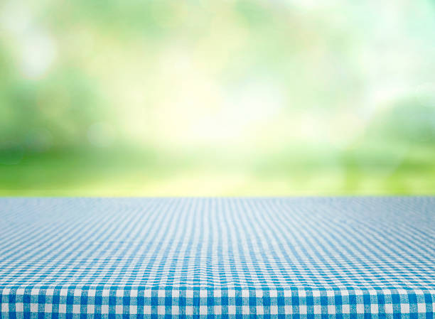 Food advertisement counter, empty gingham tablecloth with blurred green natural background,prpduct display,layout,mockup.Countryside desktop.