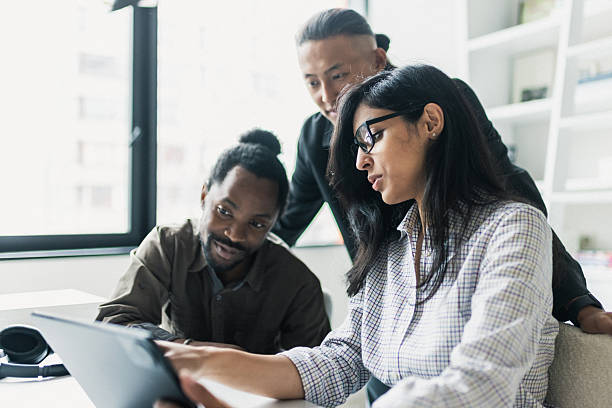 istock Diverse team collaborates around a tablet in a modern office, planning and sharing ideas. 2239914465