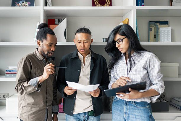 istock Three colleagues collaborate on documents in a modern office, sharing ideas and reviewing plans. 2239914736