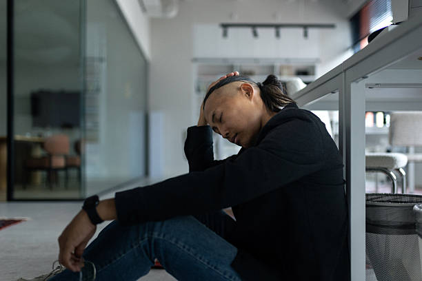 istock Man sits on the office floor, resting against a desk in a modern, quiet workspace 2239914899