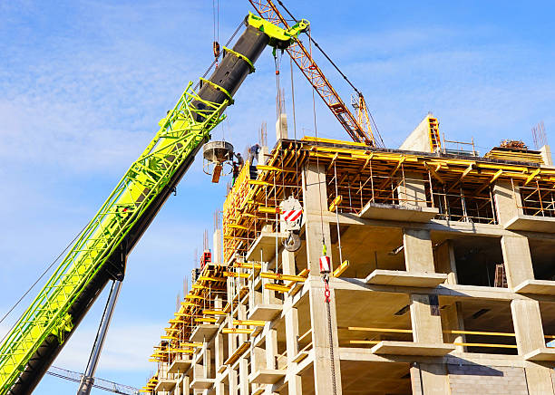 istock Building construction. Large green jib crane lifts materials to concrete structure. 2239917594
