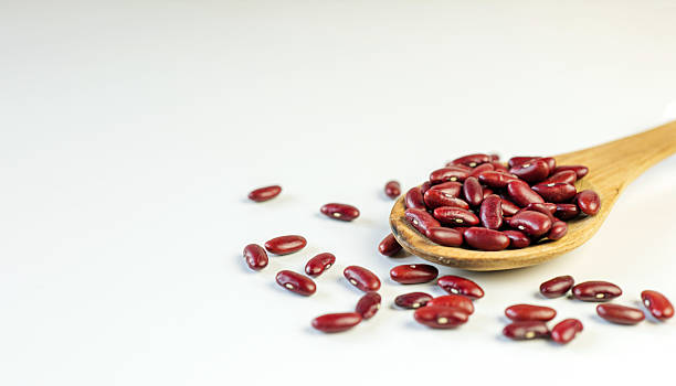 istock Red bean seeds on a wooden spoon on a white background 2239922240