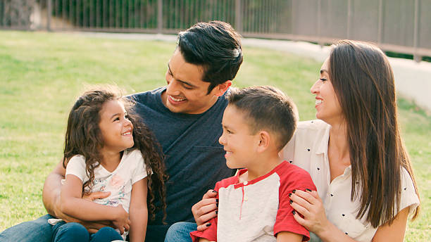 istock Smiling Family Sitting On Grass Outdoors In Park Together 2239925063