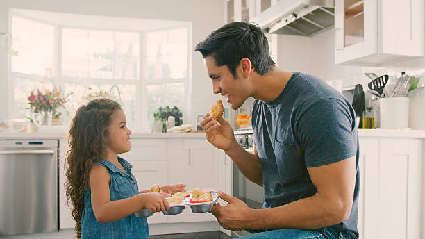 istock Father In Kitchen At Home Eating Cupcakes Baked By Daughter 2239925322