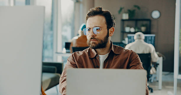 istock Reading, computer and business man in office for software development, online project or review. Laptop, serious or frontend developer with internet update, creative problem solving or website design 2239925410