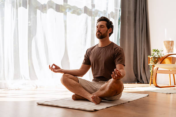 istock Bearded, middle aged man practicing meditation indoors at home sitting in lotus position 2239925996
