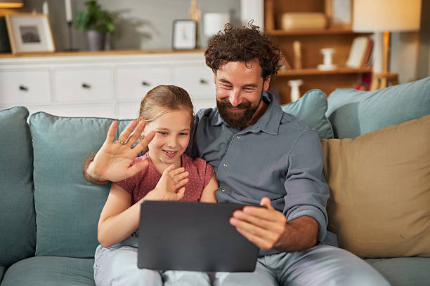 istock Father and daughter video chatting on digital tablet at home 2239927160