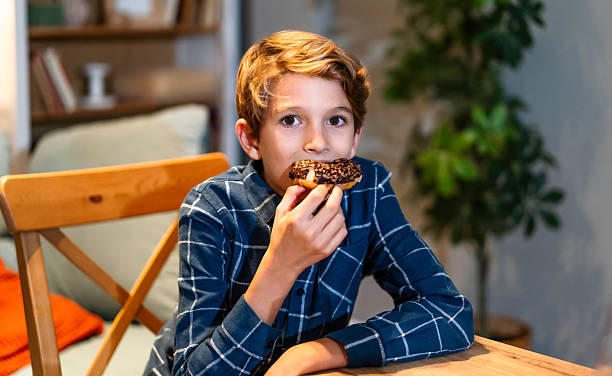 istock Boy eating a donut at home 2239928558