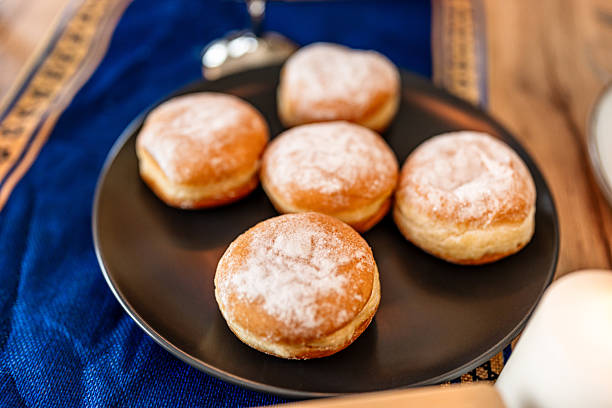 Sufganiyot donuts with powdered sugar on a black plate, symbolizing the Hanukkah holiday and Jewish tradition
