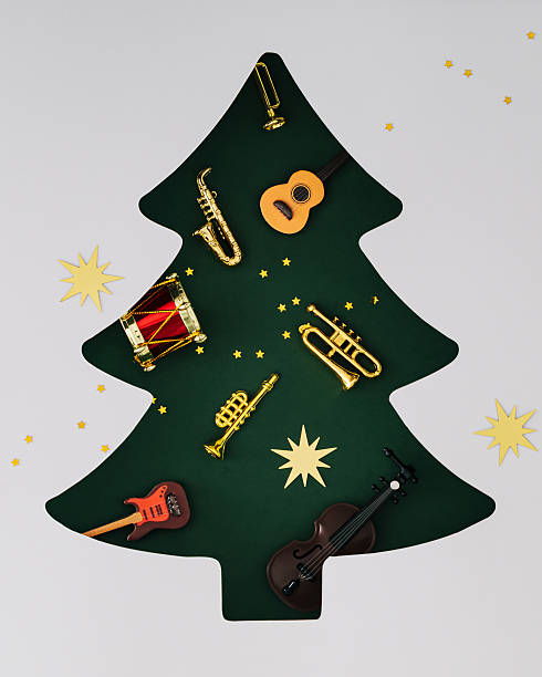 istock Musical instruments visible through a Xmas tree shaped gap on green background. Minimal Christmas and New Year concept. Creative festive holiday music idea. Celebration party flat lay. Top view. 2239933197