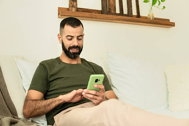 istock male amputee seating in sofa and looking at cell phone screen 2239933648