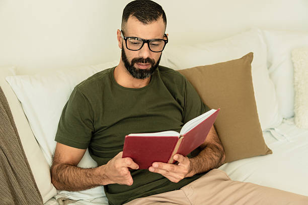 istock male amputee with glasses reading a book in sofa 2239933660