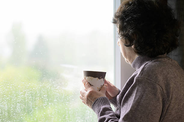 istock Senior Woman Drinking Tea by Window on Rainy Day 2239934814