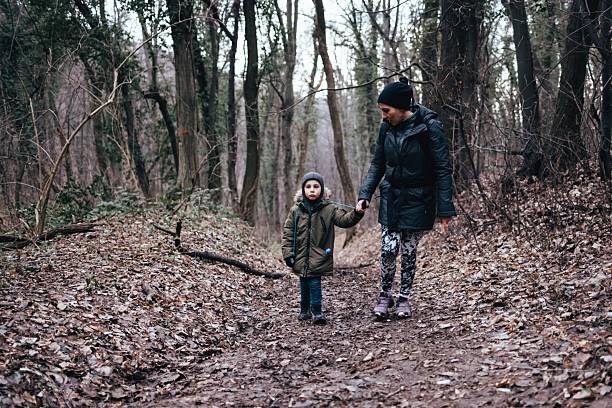 istock Mother and son walking holding hands in forest 2239938141