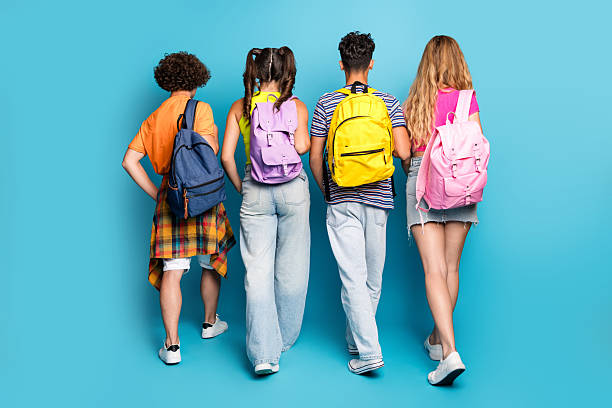 istock Playful school crew posing with bright backpacks on a vivid blue studio backdrop 2239940099