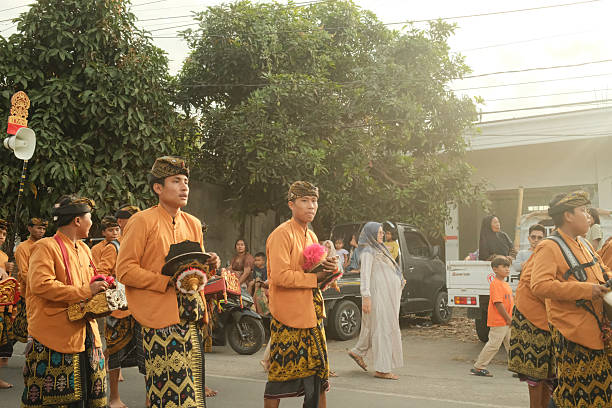Lombok Island, Indonesia - September 07, 2025: Group of Balinese men dressed in traditional clothing parading down a street during a cultural ceremony in Indonesia