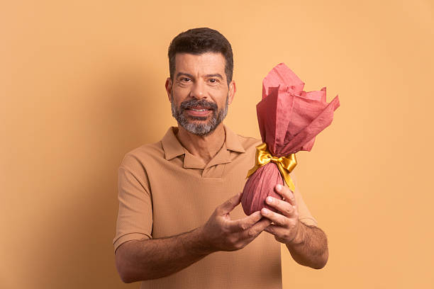 istock joyful caucasian man offering easter egg in beige colors. holiday, easter, celebration concept. 2239945595