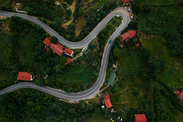 Winding road curving through a lush green rural landscape with scattered houses
