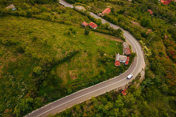 Winding road curving through green hills with a car and houses